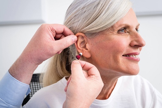 Ältere Frau bekommt ein modernes Hörgerät eingesetzt, Hörakustik und Hörhilfe Beratung.